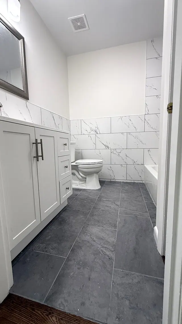Bathroom remodel with gray tile floor vanity and toilet by Grain and Stain Renovations in Hendersonville TN