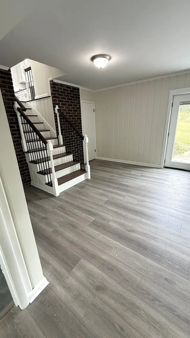 Finished basement with gray LVP flooring and staircase by Grain and Stain Renovations in Hendersonville TN