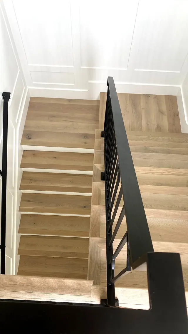 Light oak staircase with black railing installation by Grain and Stain Renovations in Hendersonville TN
