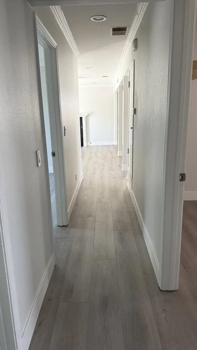 Long hallway with gray LVP flooring and white trim by Grain and Stain Renovations in Hendersonville TN