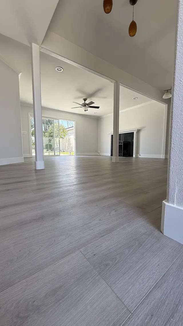 Open living room with gray LVP flooring and fireplace by Grain and Stain Renovations in Hendersonville TN